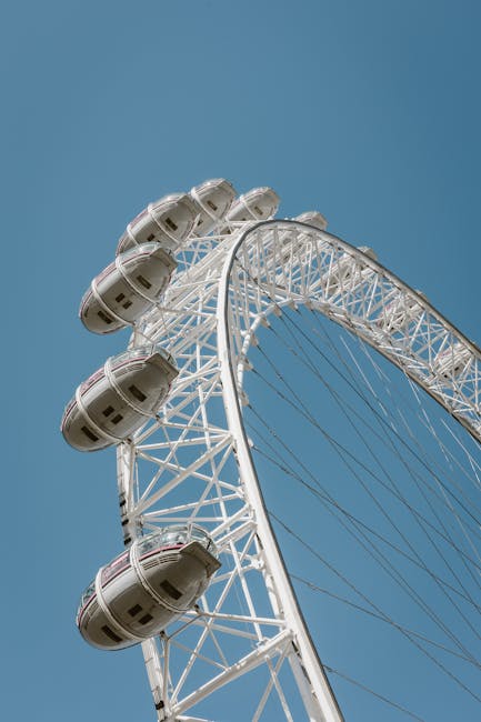 A close-up view of the London Eye Ferris wheel against a clear blue sky, showing the white metallic structure and the glass capsules attached to the rim, illuminated by natural sunlight. The image captures the detailed lattice framework supporting the capsules, emphasizing cleanliness and structural integrity, with no visible dirt or debris. This photo exemplifies the importance of surface cleaning and maintenance in ensuring the safety and aesthetic appeal of large-scale entertainment attractions, aligning with the principles of sanitisation and deep cleaning highlighted by Cleaners Lambeth for residential and commercial spaces. Proper upkeep of such structures requires meticulous surface cleaning of metal, glass, and structural components to maintain hygiene and safety standards, essential aspects of professional cleaning services provided in Lambeth.